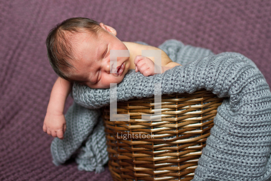 Newborn baby boy in blanket and wicker basket