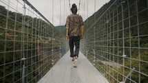 Man walking over a bridge during tour in Baños de agua santa, Ecuador