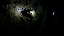 a woman with a headlamp exploring a dark cave 