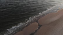 Aerial view of calm waves hitting the beach.