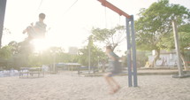 Children riding swings together at a public playground.