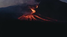 Drone aerial view of silhouette of people next to lava from Pacaya Volcano eruption at night in Guatemala	