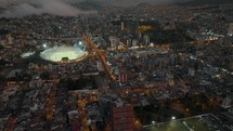 Aerial View Of Atahualpa Olympic Stadium, traffic, and Quito skyline at night in Ecuador.	