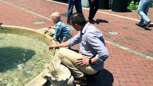 a father and son playing in a fountain 