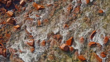 Mountain stream with crystal clear water flowing over stones at daytime. Top down shot, calming nature background
