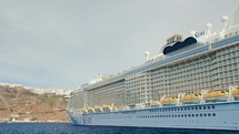Luxuary Giant cruise ship docked in Santorini bay in greece under sunny day vacation holiday time.