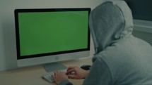 Man in a hoodie working on a computer