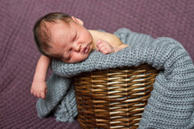 Newborn baby boy in blanket and wicker basket