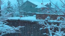 Snow falling on fence and houses