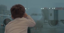 Boy waiting for the flight and looking at airplanes outside