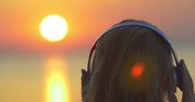 Woman enjoying music and sunset