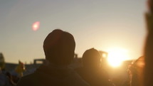 people walking around at an outdoor festival at sunset 