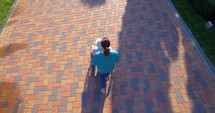 Aerial footage of nurse pushing elderly woman on wheelchair outdoors in city park in summer. 4k