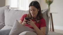 Charming woman with smartphone read messages from boyfriend smiling at home. 
