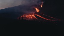 Sunrise silhouette of people next to the lava coming down from Pacaya volcano eruption in Guatemala - Drone Aerial Night-time shot	