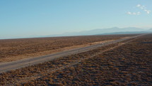 Highway through desert-like landscape in Argentina, the car is riding along the road. Aerial view, drone shot
