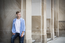 teen boy posing leaning against a marble column 