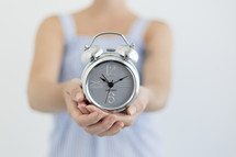 woman holding an alarm clock in cupped hands 
