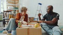 Young family couple eating delicious pizza and enjoying it when resting together on the floor in the living room under renovation. Zoom Shot
