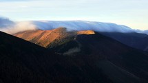 Clouds roll over the mountain ridge, Autumn morning in Carpathian nature, timelapse
