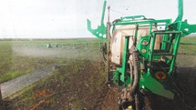 Tractor spraying green wheat field. Industrial machine fertilizing a field. Chemicals used by agricultural tractor.