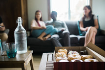 box of donuts and people sitting on a couch 