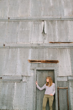 a woman standing in front of a building made of sheet metal 