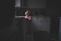 toddler girl playing in a kitchen sink 