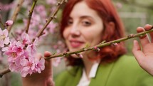 Red haired woman posing with a cherry blossom tree.