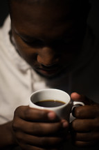man holding a coffee mug with head bowed 