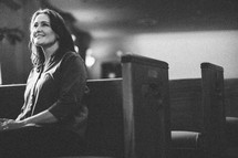 woman sitting in a church pew smiling 