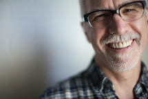 face of a man with a white beard wearing reading glasses 