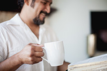 man reading a Bible and drinking coffee
