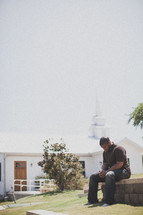 man praying outside in front of a church 