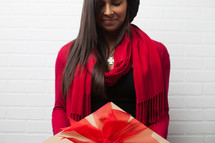 an African American woman with head bowed holding a wrapped Christmas gift 