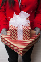hands in gloves holding wrapped Christmas gifts 