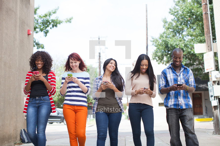young adults walking and texting on their cellphones 