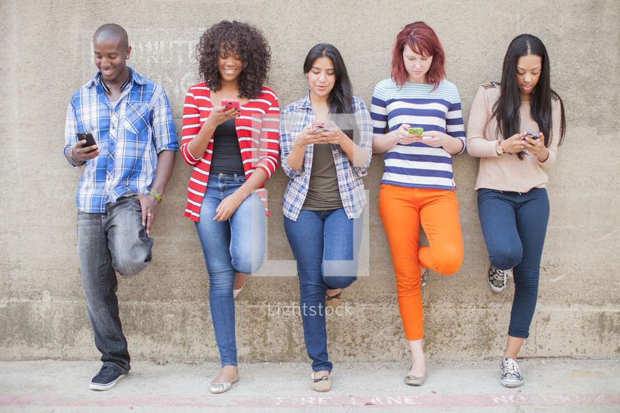 a row of young adults checking their cellphones