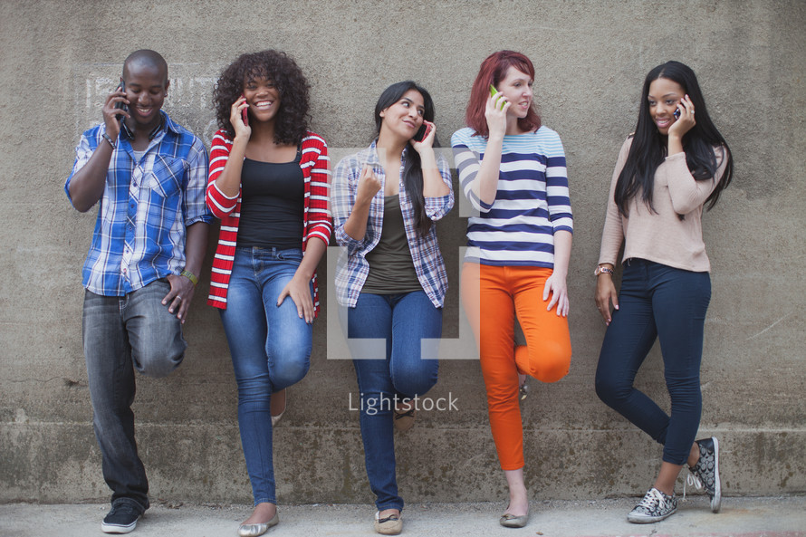 a row of young adults adults talking on a cellphone 