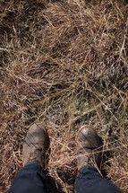 boots standing in dry grasses 