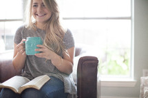 woman drinking coffee and reading a Bible on her lap 