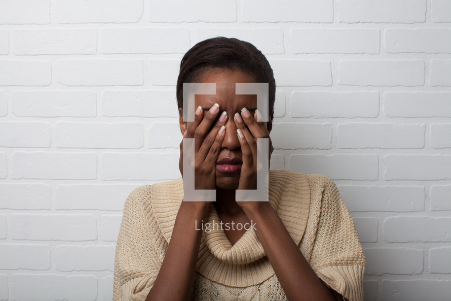 African-American woman with covering her face with her hands 