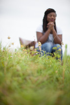 woman sitting in a chair in a field in prayer 
