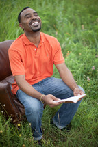 joyful man reading a Bible outdoors 