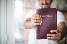 A man holding a Bible out in front of him.