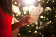 An African American woman holding an Angel Christmas ornament 