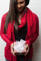 An African-American woman holding a Christmas gift with her head bowed in prayer 