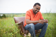 African-American man sitting in a chair in a field relaxing 