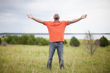man standing in a field with open arms 