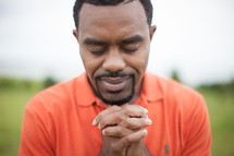 man with praying hand outdoors 